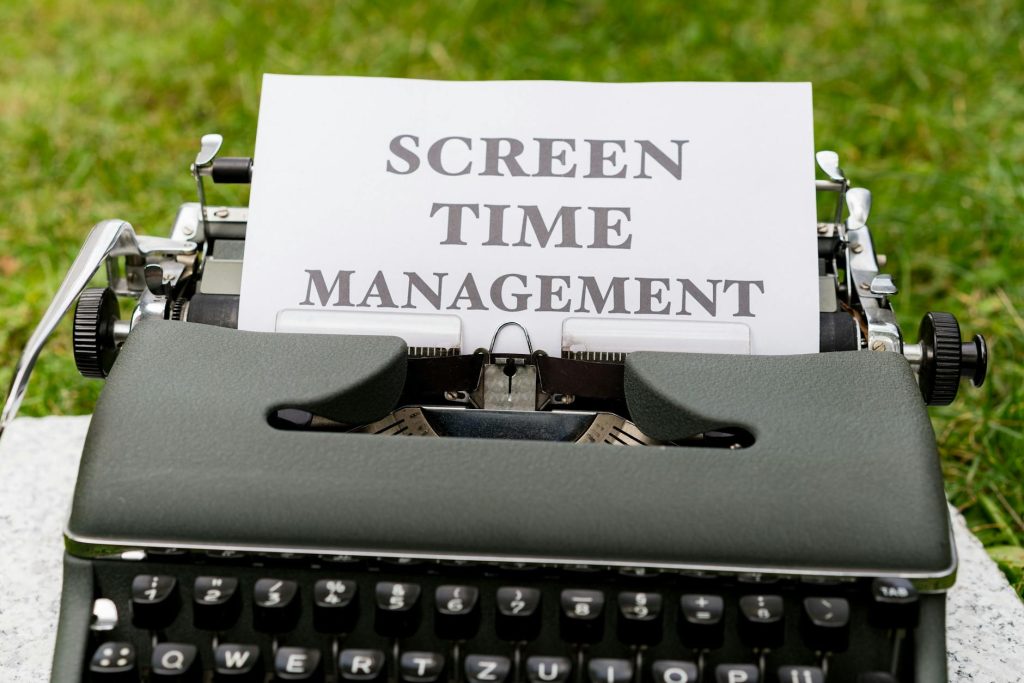 Retro typewriter displaying 'Screen Time Management' on paper outdoors.